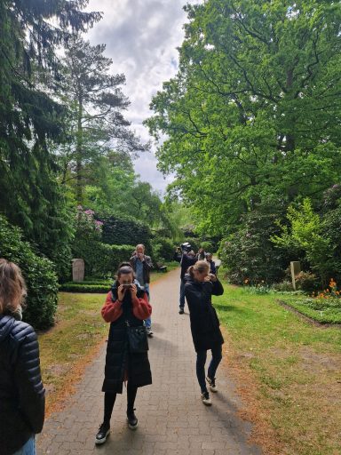 Gruppe von Personen spaziert auf einem Weg durch einen grünen Park.